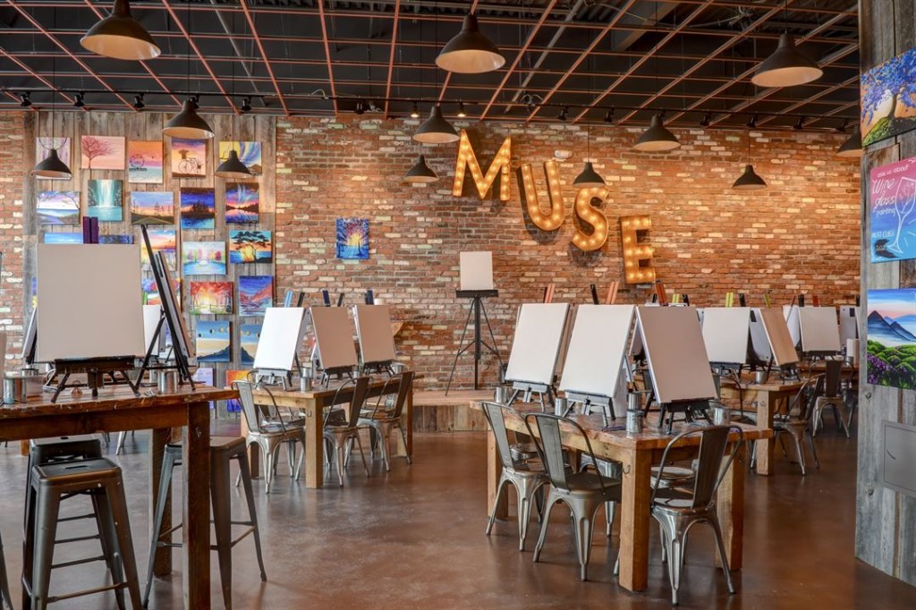 Muse Paintbar studio with easels and marquee sign